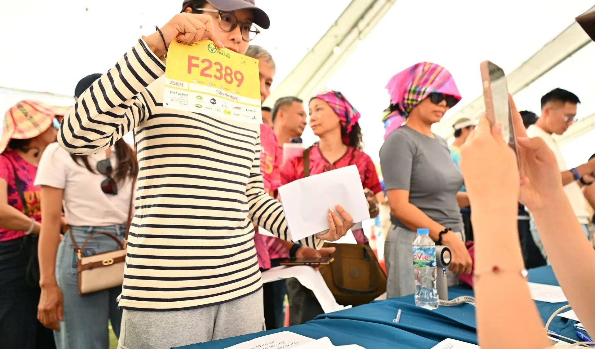 A participant holds up the bib just collected at the desk
