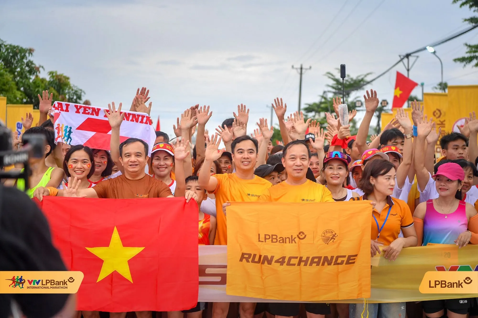 Runners raise their hands with a red-star flag and a Run4Change banner at the start line