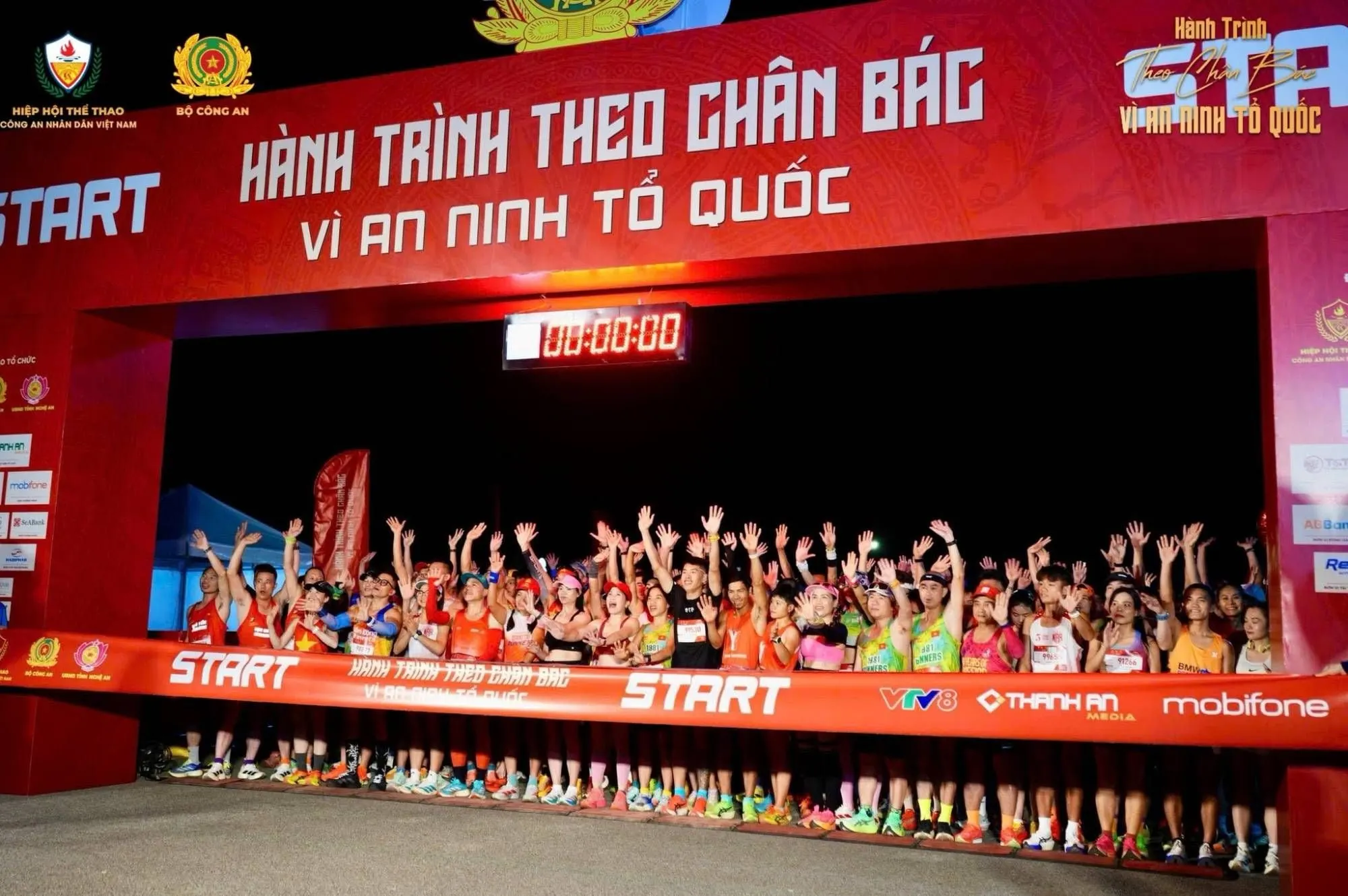 Vận động viên giơ tay dưới cổng xuất phát lúc trời tối, đồng hồ 00:00:00