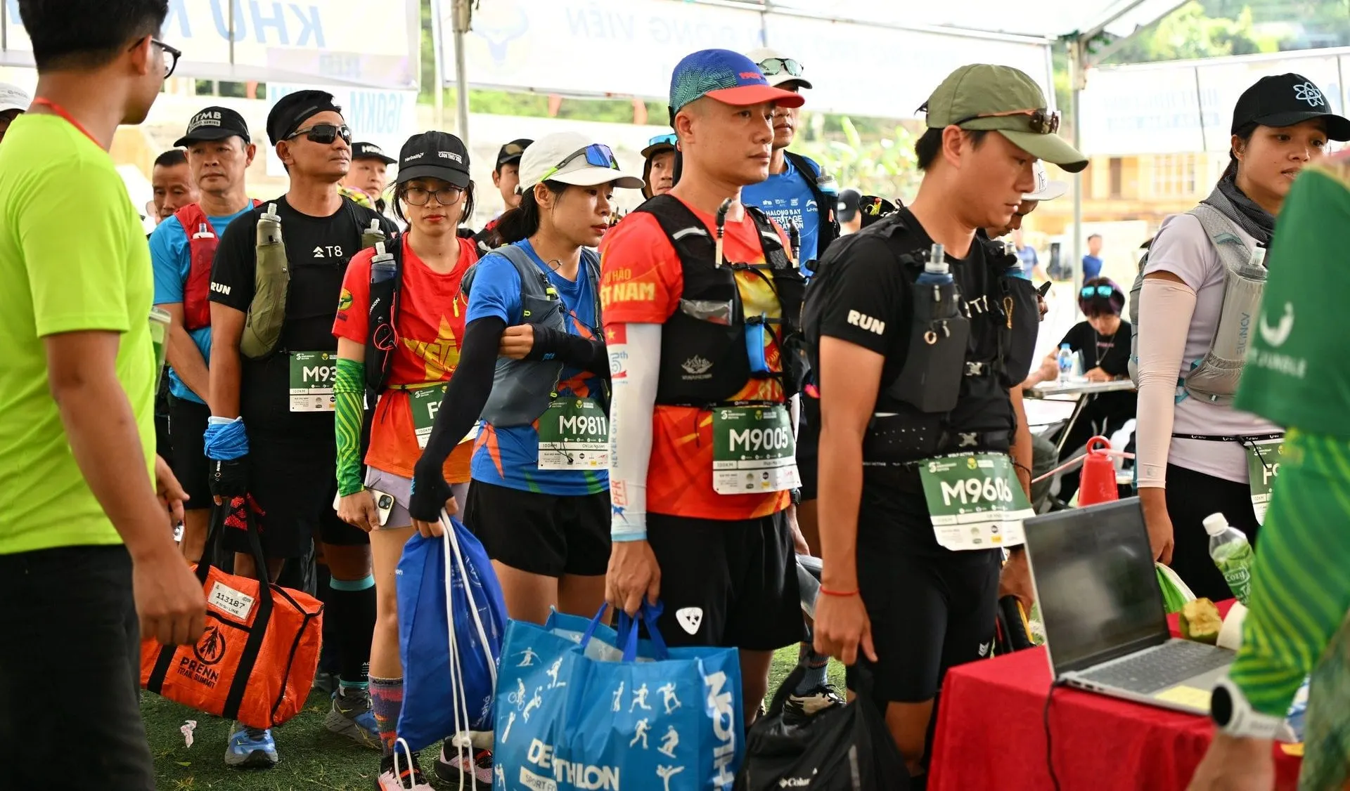 Participants with backpacks queue for check-in before the start