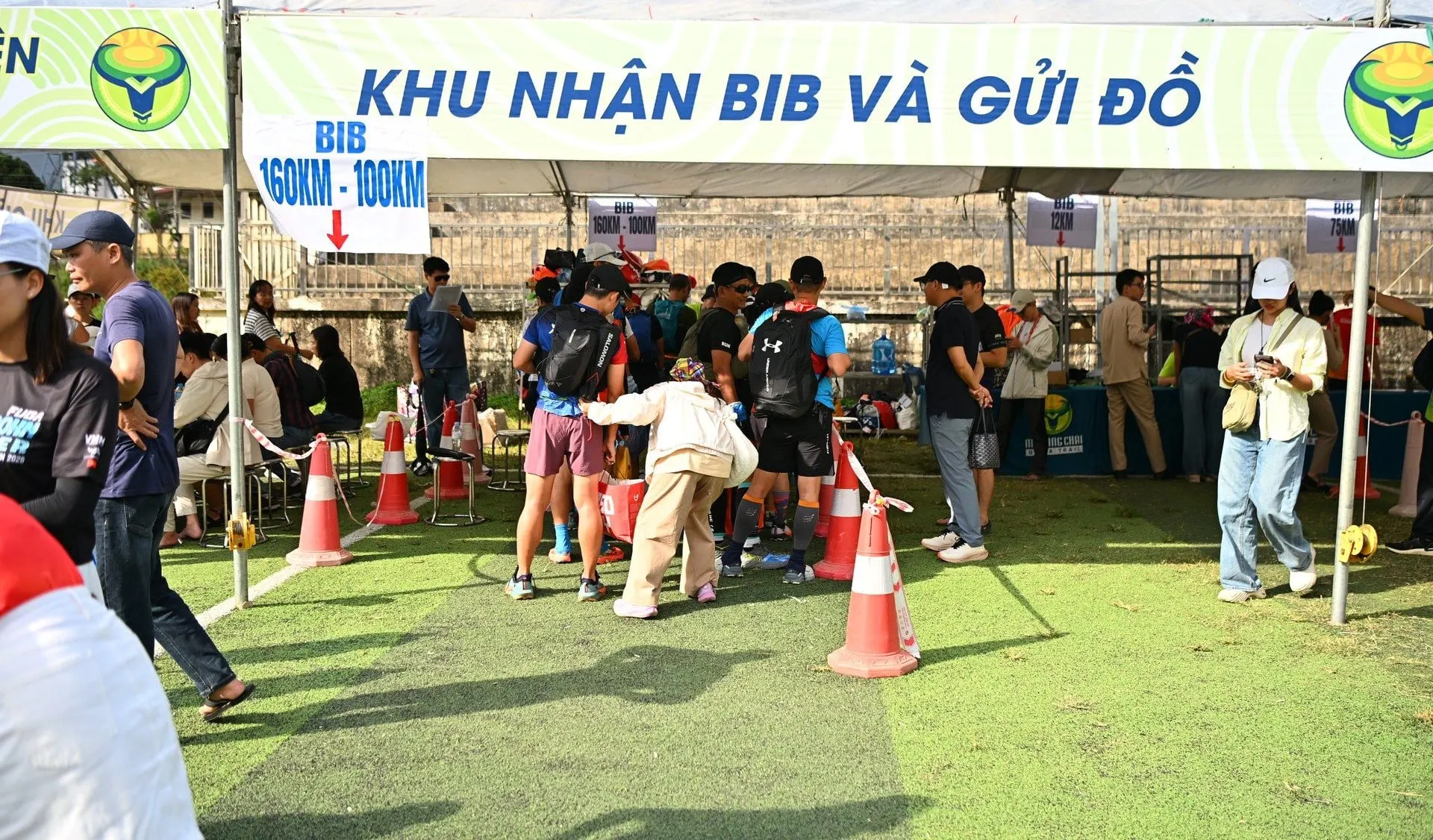 Bib pickup under a large tent, participants queuing by distance