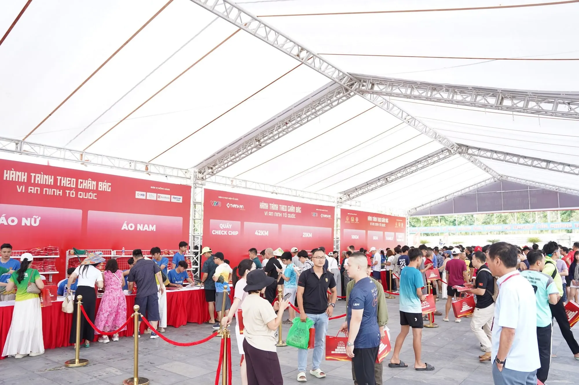 A long queue of participants under the race-kit pickup canopy