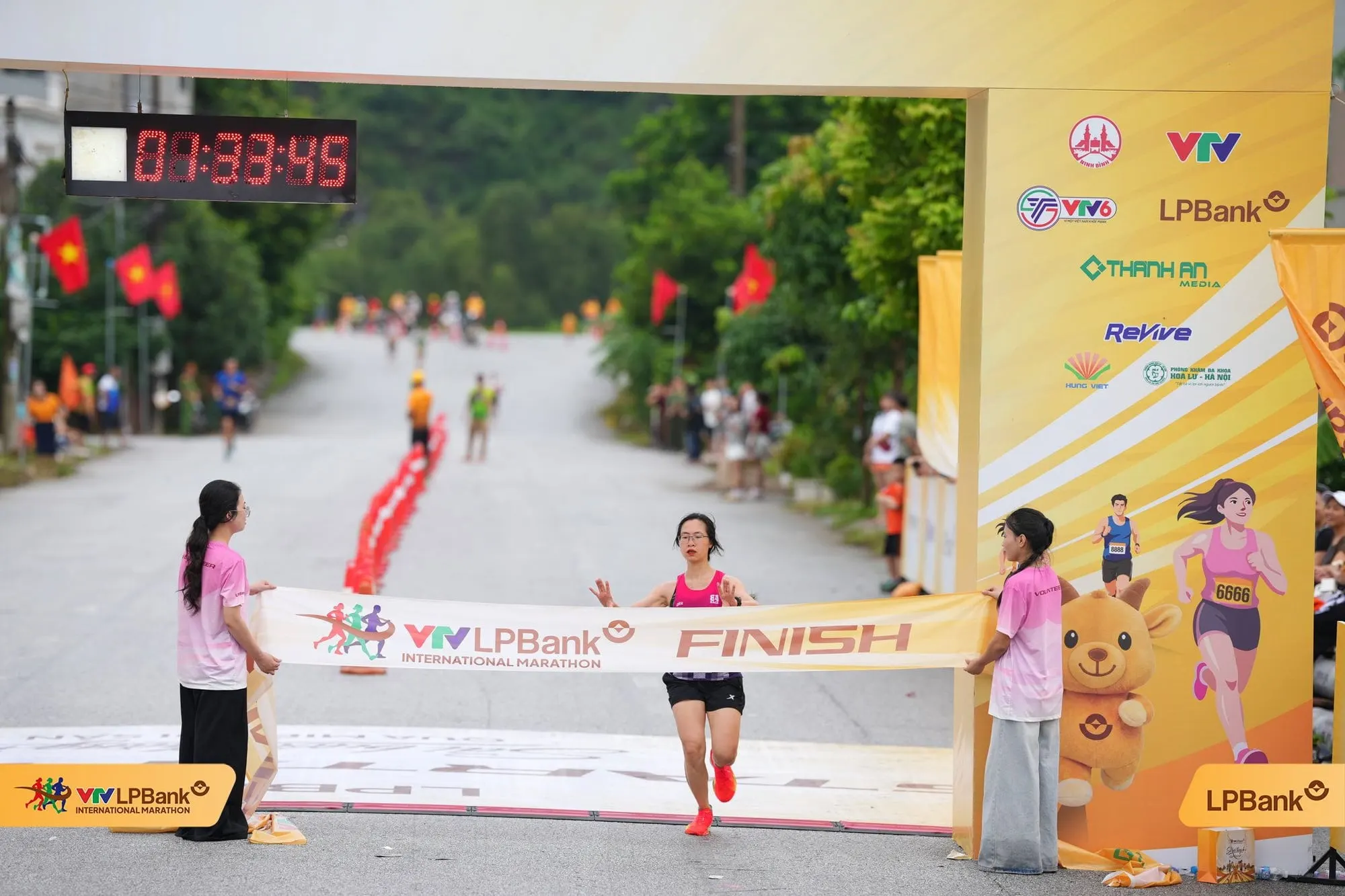 Nữ vận động viên chạm băng FINISH, đồng hồ 01:33:45, núi phía sau