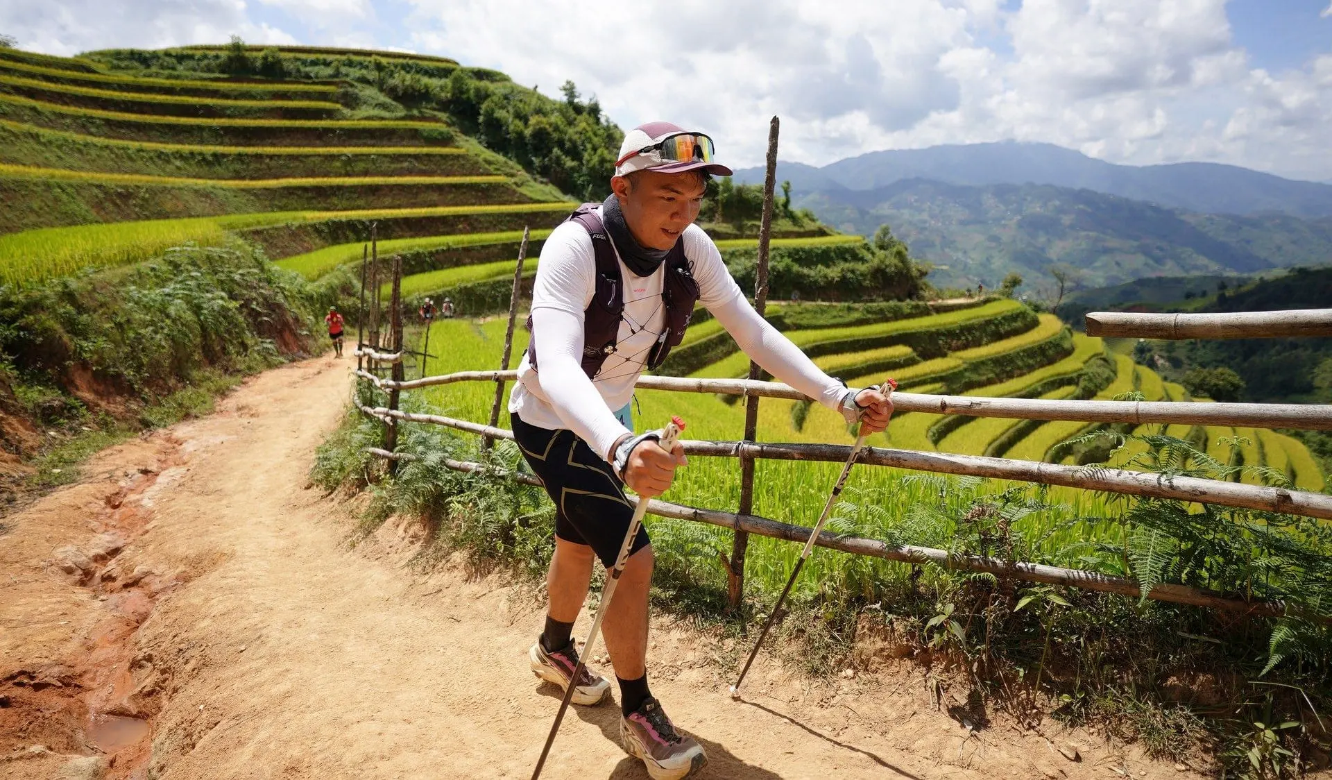 A trail runner with poles beside rice terraces