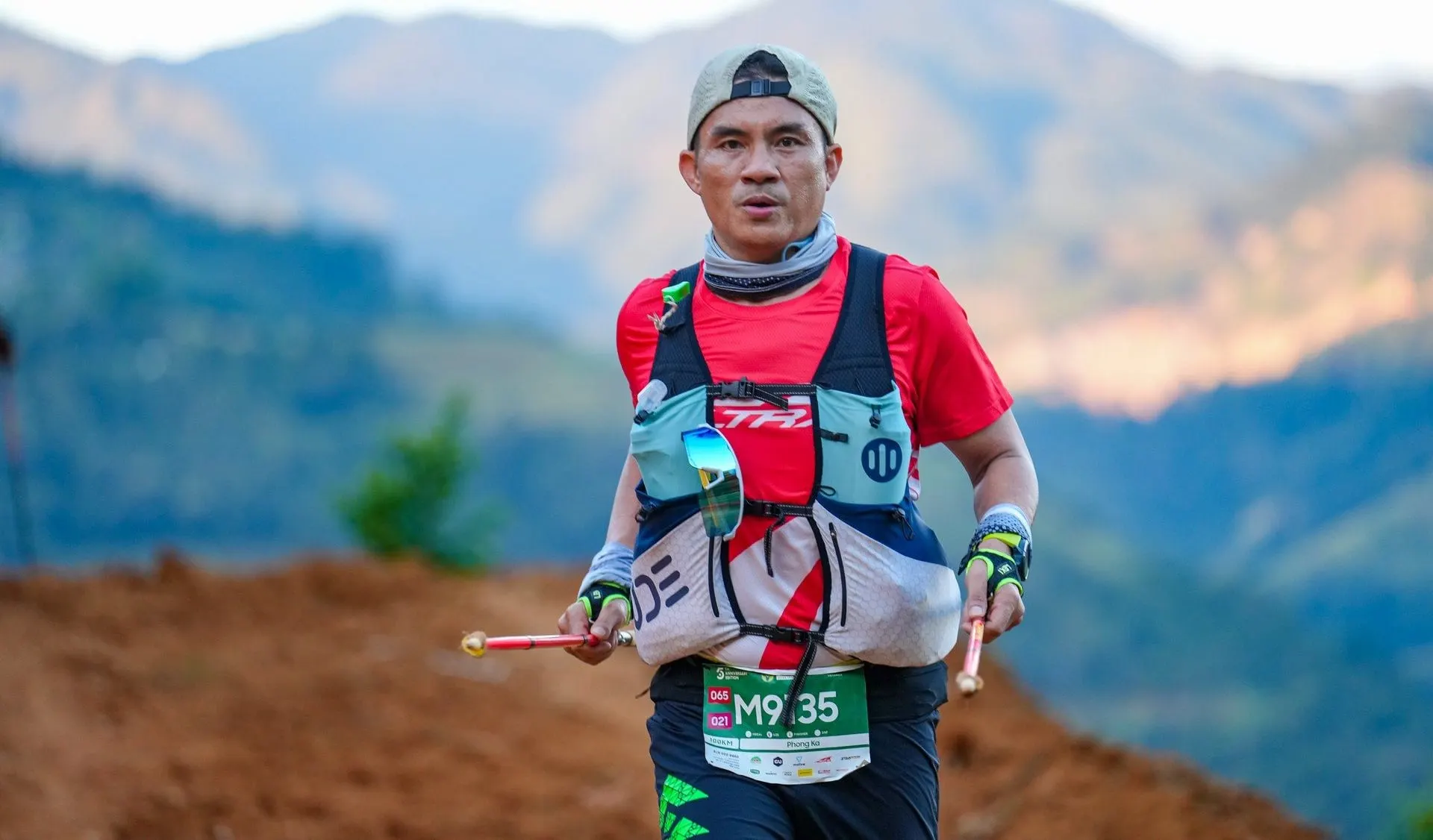 A trail runner on a ridge, misty mountains behind