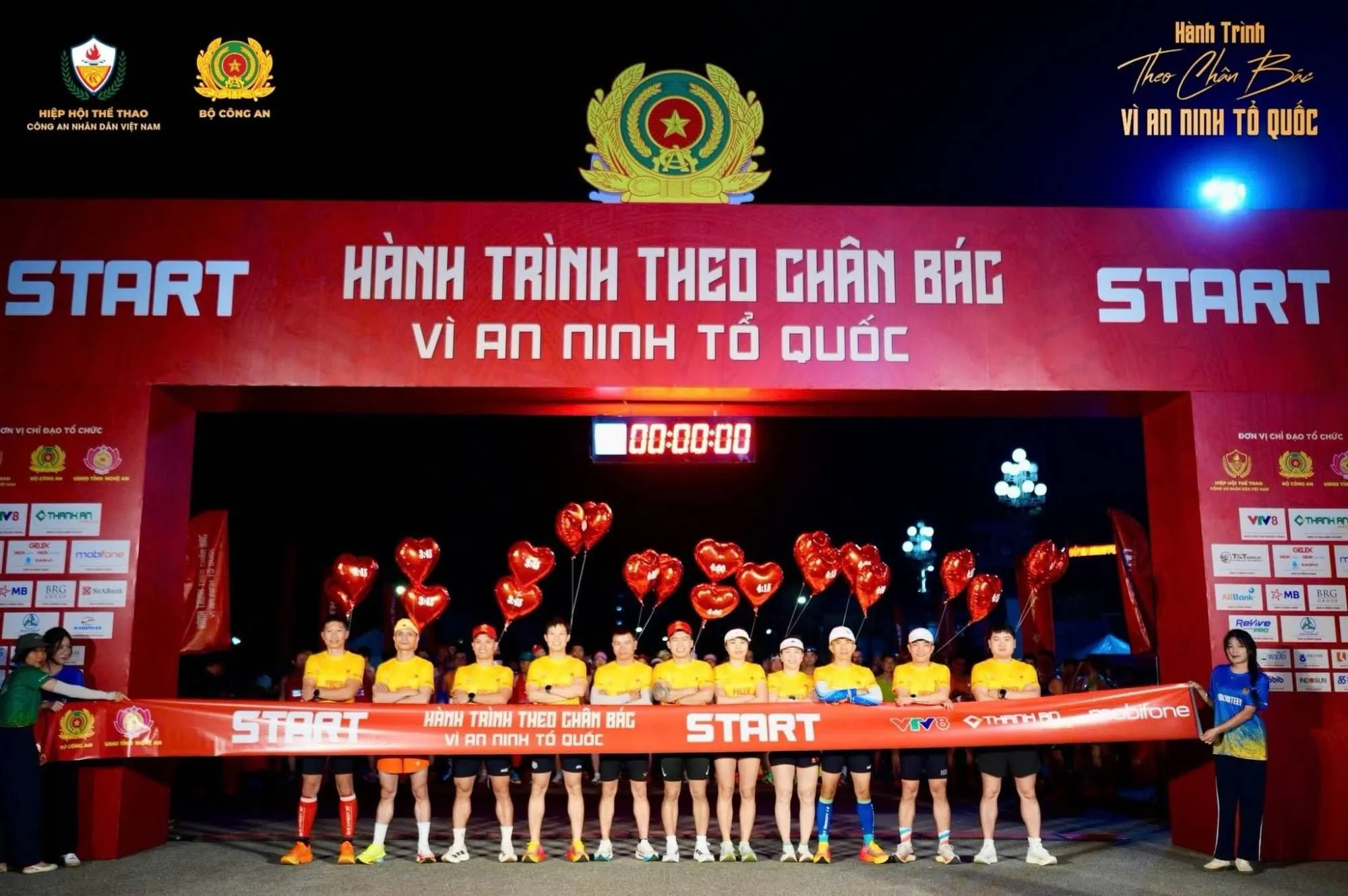 A row of pacers in yellow holding time balloons behind the start tape