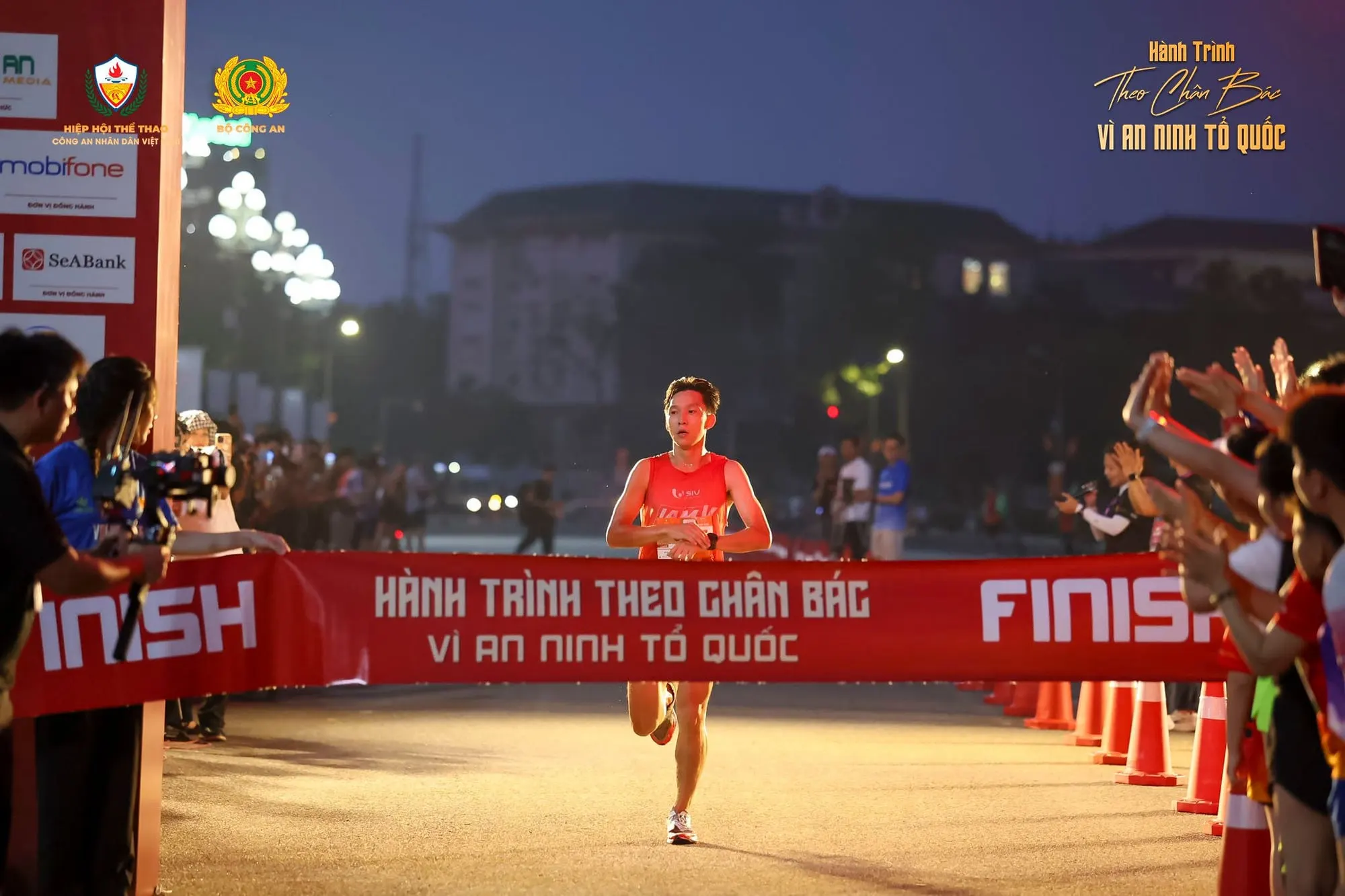 A runner heads for the finish tape as spectators reach out to cheer