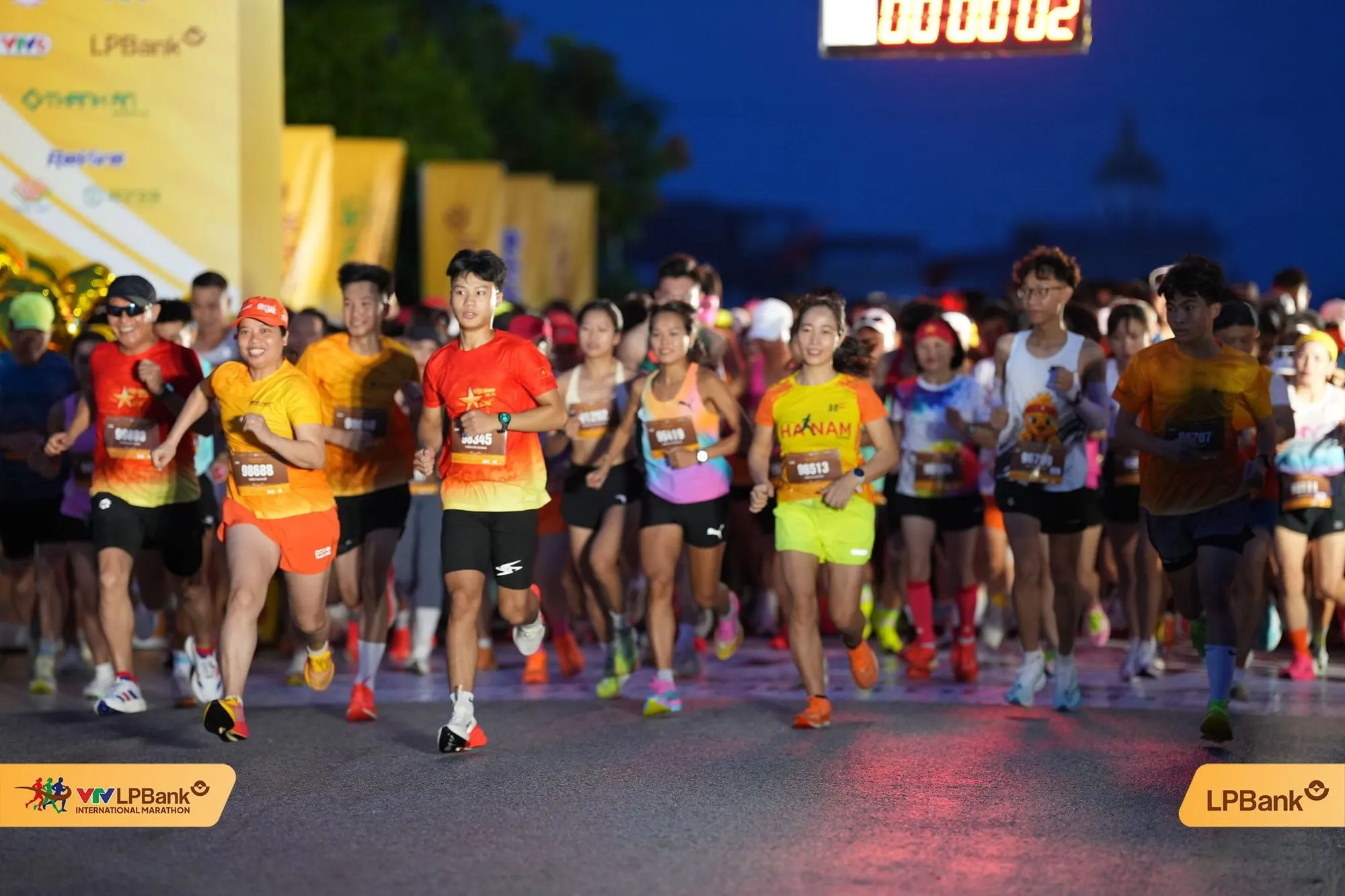Runners pour out of the start arch before dawn